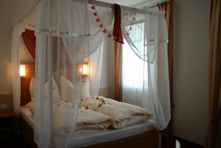 Weisses Himmelbett, dekoriert mit Rosenblättern